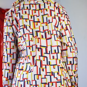 May include: A white long-sleeved shirt with a geometric pattern in red, blue, and yellow.
