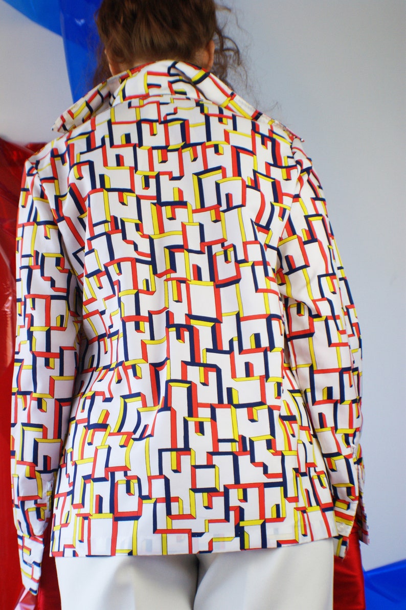 May include: A white long-sleeved shirt with a geometric pattern in red, blue, and yellow.