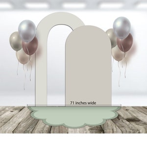 May include: A backdrop for photos with two arched panels in white and a light green cloud-shaped base. The backdrop is 71 inches wide and decorated with a cluster of balloons in shades of brown, beige, and silver.