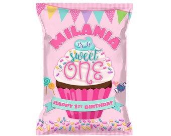 May include: Pink and white chip bag with a cupcake design. The cupcake has pink frosting and sprinkles. The text on the bag reads "Milania is a sweet one" and "Happy 1st Birthday".