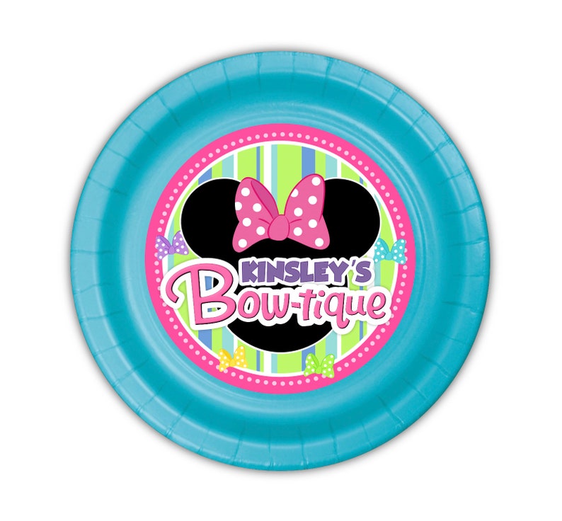 Puede incluir: Un plato de papel redondo azul claro con un dise&ntilde;o de Minnie Mouse. El centro presenta una silueta negra de la cabeza de Minnie con un lazo rosa de lunares. El texto "Kinsley's Bow-tique" se muestra en rosa y morado.
