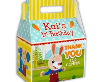 Może przedstawiać: Żółte, niebieskie i zielone pudełko na upominki z ilustracją królika. Pudełko ma uchwyt i napis "Kai's 1st Birthday" oraz "Thank You for Coming!"