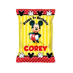 May include: A yellow and red party favor bag with a Mickey Mouse character, the words "Happy 1st Birthday" and the name "COREY".