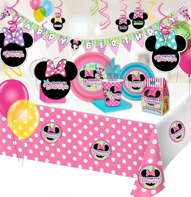 Puede incluir: Una escena festiva de fiesta de cumplea&ntilde;os con decoraciones tem&aacute;ticas de Minnie Mouse. Incluye un mantel rosa con lunares blancos, globos, platos, vasos y una pancarta que dice "Happy Birthday". La combinaci&oacute;n de colores es rosa, negro y blanco.