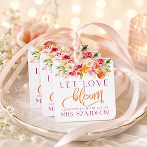 May include: Three square white gift tags with rounded corners, each featuring a watercolor floral design in pink, orange, and green. The text reads LET LOVE bloom COMPLIMENTS OF THE FUTURE MRS. SZAJDECKI. A light pink satin ribbon ties the tags together.