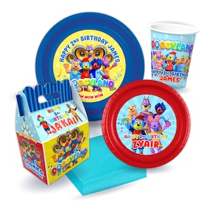 May include: A set of party supplies featuring the characters from the children's show Doggyland. The set includes a blue and white paper plate, a red paper plate, a blue and white paper cup, a blue and white favor box, and a blue napkin. The plates and cup feature the Doggyland characters and the text "Happy 2nd Birthday James" and "Happy 3rd Birthday James". The favor box features the Doggyland characters and the text "Happy 2nd Birthday Ja'Kai".