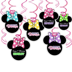 Puede incluir: Decoraciones de fiesta negras con forma de Minnie Mouse con lazos de lunares en varios colores, incluyendo rosa, azul, amarillo y verde. El texto "KINSLEY'S Bow-tique" y "Happy 1st Birthday KINSLEY" se muestran, con serpentinas rosas.