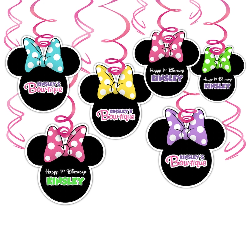 Puede incluir: Decoraciones de fiesta negras con forma de Minnie Mouse con lazos de lunares en varios colores, incluyendo rosa, azul, amarillo y verde. El texto "KINSLEY'S Bow-tique" y "Happy 1st Birthday KINSLEY" se muestran, con serpentinas rosas.