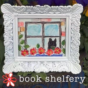 May include: White framed artwork featuring a watercolor painting of a window with a black cat, red flowers, and the text "book shelfery". The frame has ornate detailing.
