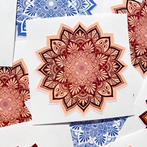 Pu&ograve; includere: Un set di quattro adesivi mandala in vari colori, tra cui blu, rosso, arancione e rosa. Gli adesivi sono stampati su carta bianca e presentano disegni intricati.