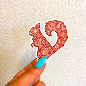 May include: A red floral patterned sticker of a squirrel with a heart-shaped tail.