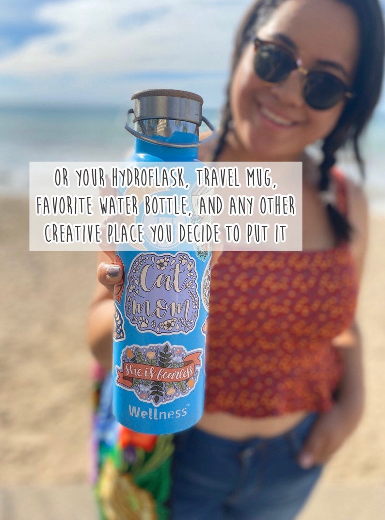 Pu&ograve; includere: Una bottiglia d'acqua riutilizzabile blu con un coperchio in acciaio inossidabile e diversi adesivi. Gli adesivi presentano motivi floreali e testo che recita "Cat Mom", "She is fearless" e "Wellness".