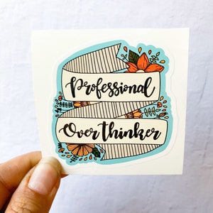 May include: A blue and white striped banner with the text "Professional Overthinker" in black script. The banner is decorated with orange and yellow flowers.