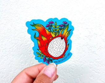 Könnte beinhalten: Ein Aufkleber mit einer farbenfrohen Illustration einer Drachenfrucht mit weißen Punkten, umgeben von grünen Blättern und rosa Blüten. Der Aufkleber hat einen blauen Hintergrund und den Text "@michaelflakcreations" unten.