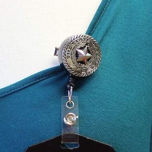 May include: Silver retractable badge holder with a round, silver charm featuring the words "The State of Texas" and a five-pointed star.