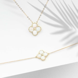May include: Two gold necklaces with a four-leaf clover pendant featuring white opal stones.