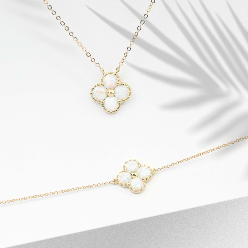 May include: Two gold necklaces with a four-leaf clover pendant featuring white opal stones.