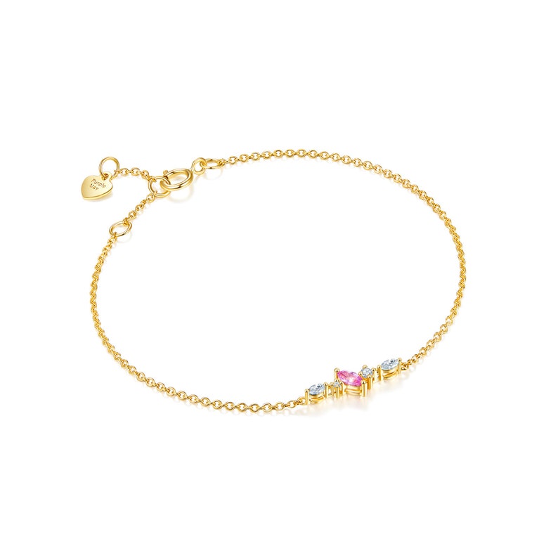 May include: A delicate gold chain bracelet with a small cluster of pink and white gemstones. The bracelet has a heart-shaped charm with the word "Forever" inscribed on it.