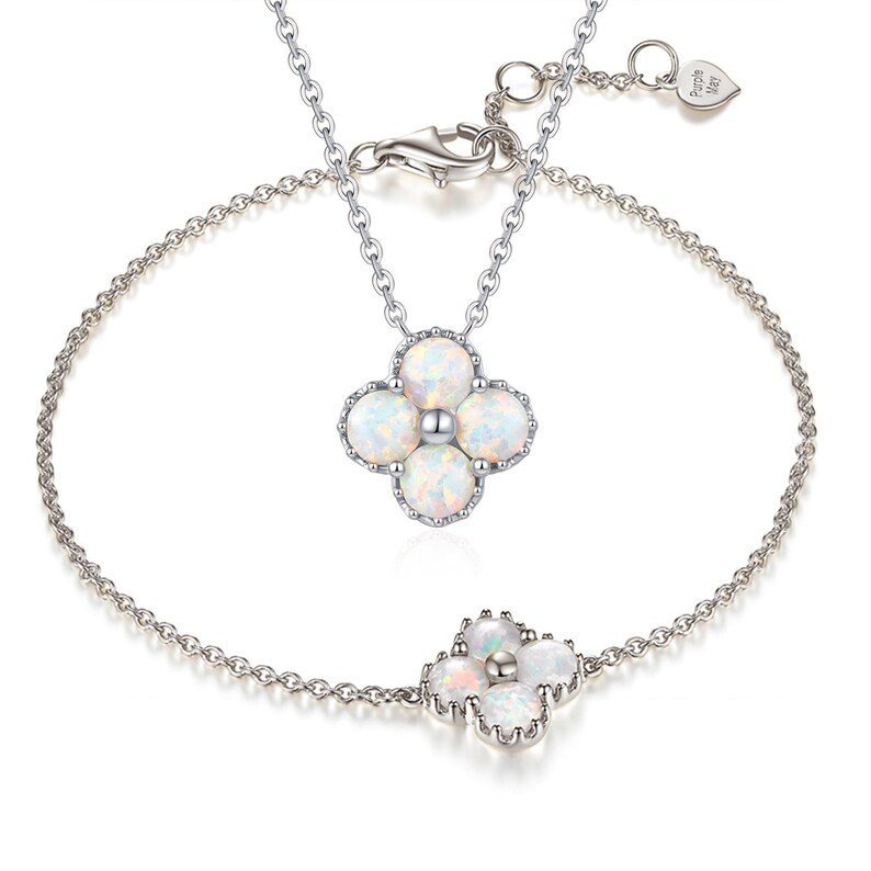 May include: A silver necklace and bracelet set with a white opal flower pendant and charm. The necklace and bracelet feature a delicate chain.