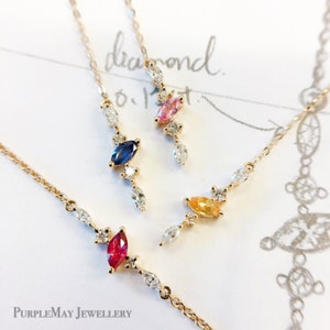 May include: Four delicate gold necklaces with a single marquise-shaped gemstone and small diamond accents. The gemstones are pink, blue, yellow, and red.