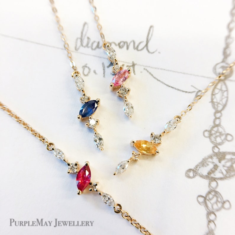 May include: Four delicate gold necklaces with a single marquise-shaped gemstone and small diamond accents. The gemstones are pink, blue, yellow, and red.