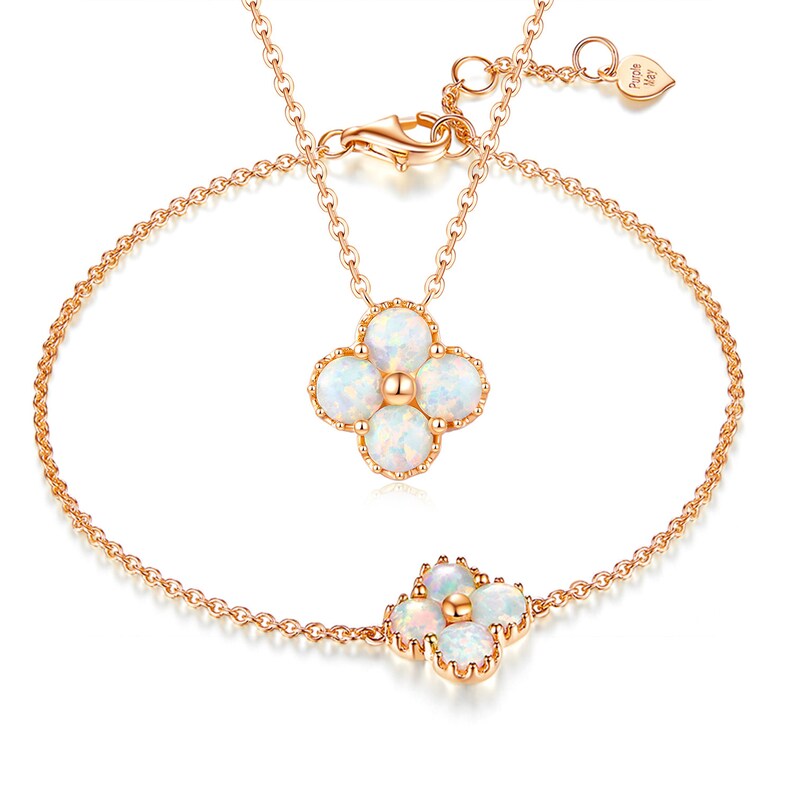 May include: A rose gold necklace and bracelet set with a delicate flower pendant and matching bracelet charm. Each piece features five white opal stones set in a floral design.