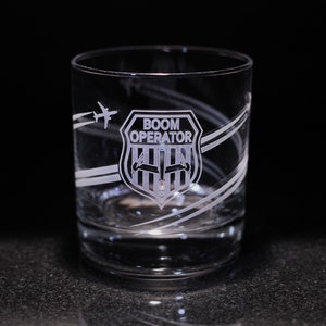 May include: A clear glass tumbler with a white etched design of a plane and the words "BOOM OPERATOR" inside a shield.