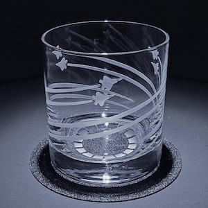 May include: A clear glass tumbler with a white etched design of fighter jets flying in formation. The glass is on a black coaster.