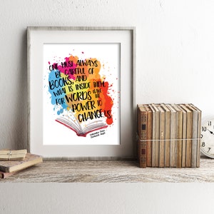 May include: A framed print with a colorful watercolor background and an open book. The quote "One must always be careful of books, and what is inside them, for words have the power to change us." is written in black text. The quote is attributed to "Aleksander Hemon,  The Comedian."