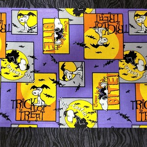 May include: Purple fabric with a repeating pattern of Snoopy dressed as a vampire with bats and the text "Trick or Treat" and "Bite!" in yellow and orange.