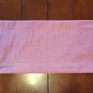 K&ouml;nnte beinhalten: Ein rot-wei&szlig; gestreifter Tischl&auml;ufer mit wei&szlig;em Stoffrand und einem festlichen Weihnachtsdruck an den Enden.