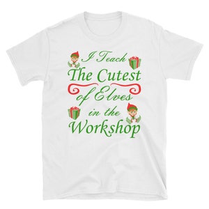 May include: White t-shirt with green and red text that reads "I Teach The Cutest of Elves in the Workshop". The text is surrounded by images of elves and presents.