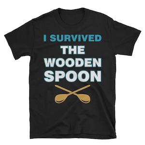 May include: Black t-shirt with the text "I survived the wooden spoon" in white and blue lettering. Two crossed wooden spoons are pictured below the text.