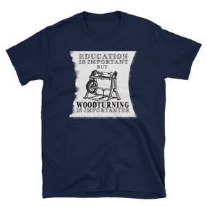 Puede incluir: Camiseta azul marino con un gráfico blanco de un torno de madera y el texto "La educación es importante, pero la torneado de madera es más importante."
