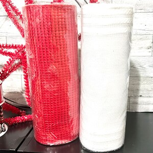May include: Two rolls of mesh ribbon, one red and one white. The rolls are wrapped in plastic and are ready to be used for crafting.