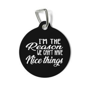 May include: Black, circular pet tag with a silver metal clip. The tag has the white text "I'M THE Reason WE CAN'T HAVE Nice things" in a whimsical font. A humorous accessory for a pet.