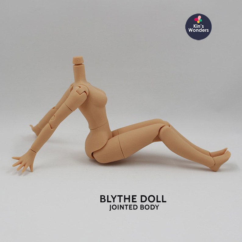 May include: A nude-colored, articulated Blythe doll body with jointed arms and legs. The doll is sitting with its legs crossed and its arms outstretched. The text "BLYTHE DOLL JOINED BODY" is printed below the doll.