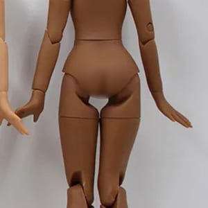May include: A brown articulated doll body with the text "EXTRA DARK" printed below. The doll is posed with its arms outstretched and legs bent at the knees.