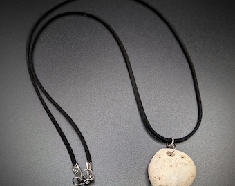 May include: A white heart-shaped stone pendant on a black cord necklace. The necklace has a silver clasp.