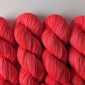 May include: Four skeins of bright coral colored yarn.