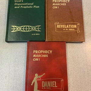 May include: Three hardcover books with gold lettering. The top left book is green and reads "God's Dispensational and Prophetic Plan." The top right book is brown and reads "Prophecy Marches On! Revelation." The bottom book is red and reads "Prophecy Marches On! Daniel."