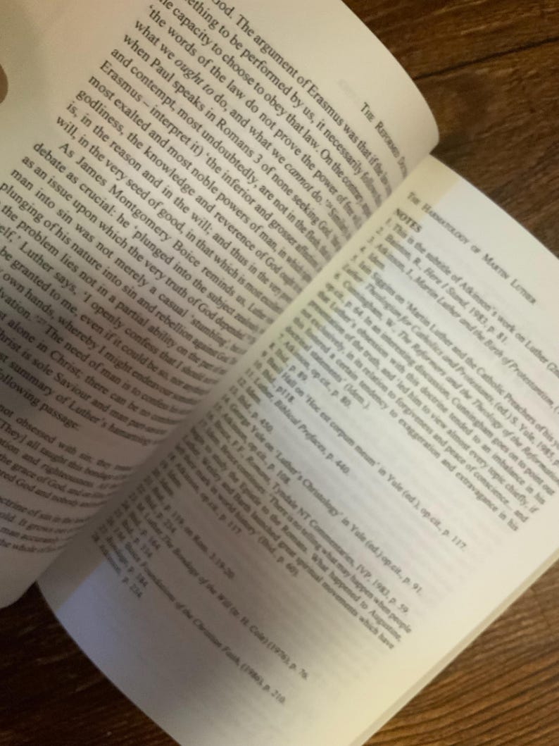 May include: Open book with text on the pages. The text is in English and includes references to Martin Luther and the Reformation. The book is open to a page with notes and citations.