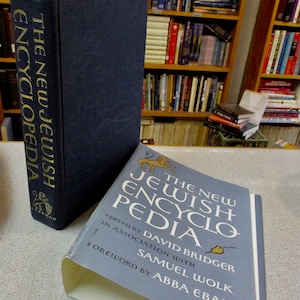 May include: Two volumes of "The New Jewish Encyclopedia" with a blue cover and gold lettering. The book on top has a lion illustration and the text "The New Jewish Encyclopedia" on the cover. The bottom book has the text "Edited by David Bridger in association with Samuel Wolk. Foreword by Abba Eban."