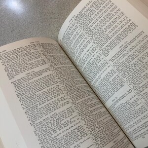 Puede incluir: Un libro abierto con texto del Libro de Job. Las p&aacute;ginas son de color blanquecino con texto negro peque&ntilde;o. El libro est&aacute; abierto en dos p&aacute;ginas enfrentadas, con el texto que llena toda la superficie. El libro est&aacute; sobre una superficie gris claro.
