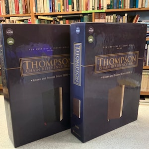 May include: Two boxed sets of the Thompson Chain-Reference Bible in the New American Standard Bible (NASB) translation. The boxes are dark blue with gold lettering and feature the title "Thompson Chain-Reference Bible" and the phrase "Known and Trusted Since 1908".