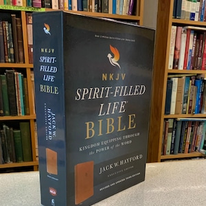 May include: A hardcover NKJV Spirit-Filled Life Bible with a dark cover and gold lettering. The book includes the text "Kingdom Equipping Through the Power of the Word" and the name Jack W. Hayford.