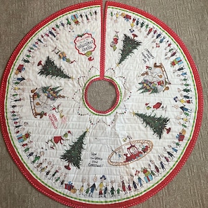 May include: A circular white quilted Christmas tree skirt featuring a red border and green trim. The fabric displays illustrations of The Grinch, Christmas trees, gifts, and characters with text reading Merry Christmas and How the Grinch Stole Christmas.