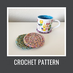 Könnte beinhalten: Drei bunte gehäkelte Untersetzer aus mehrfarbigem Garn. Die Untersetzer sind rund und haben eine strukturierte Oberfläche. Eine Tasse mit dem Text "It's a small world" steht auf den Untersetzern.