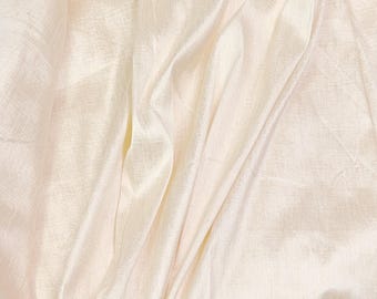 May include: Cream-colored fabric with a soft, flowing drape. The material has a subtle sheen and visible texture, with gentle folds and shadows creating depth. The fabric appears lightweight and airy, suitable for apparel or home decor.