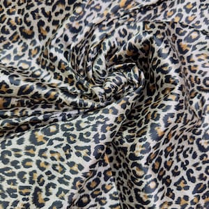 May include: Close-up of a brown and black leopard print fabric with a satin finish. The fabric is folded and draped, creating a swirling pattern.